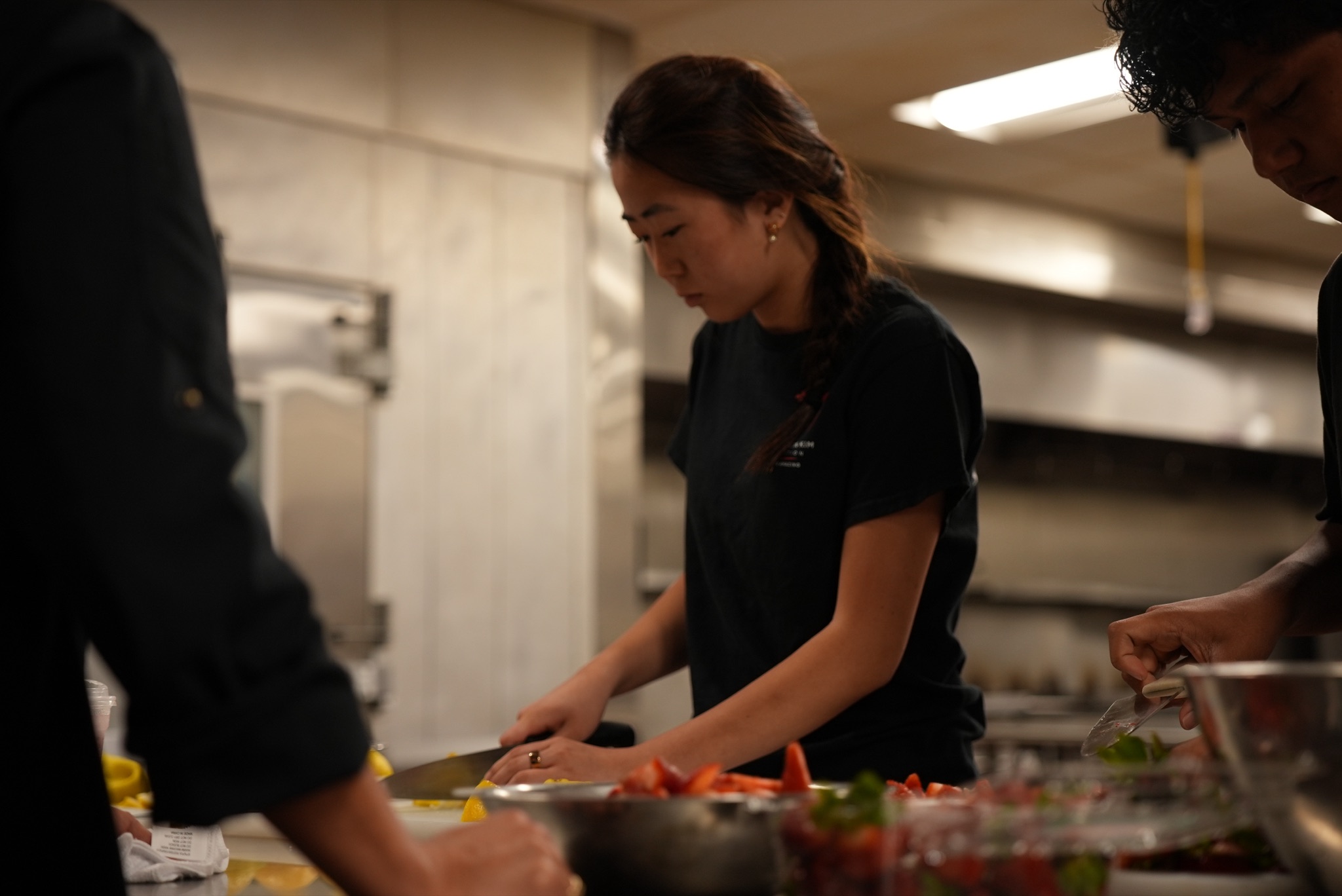 Michelle carefully preparing fresh ingredients at a commercial kitchen workstation